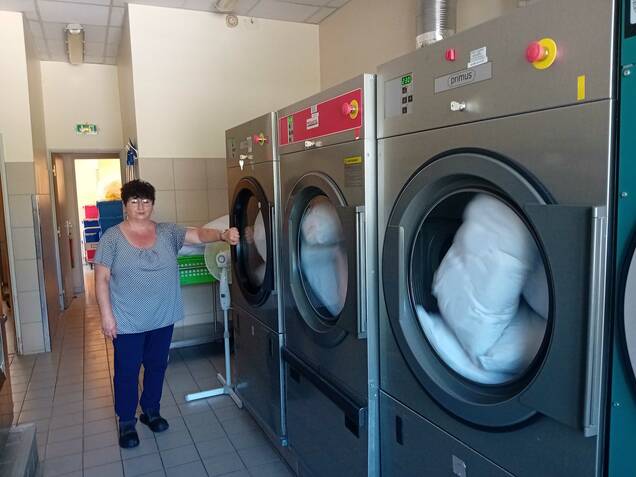 Photo d'un agent devant les machines à laver de la laverie